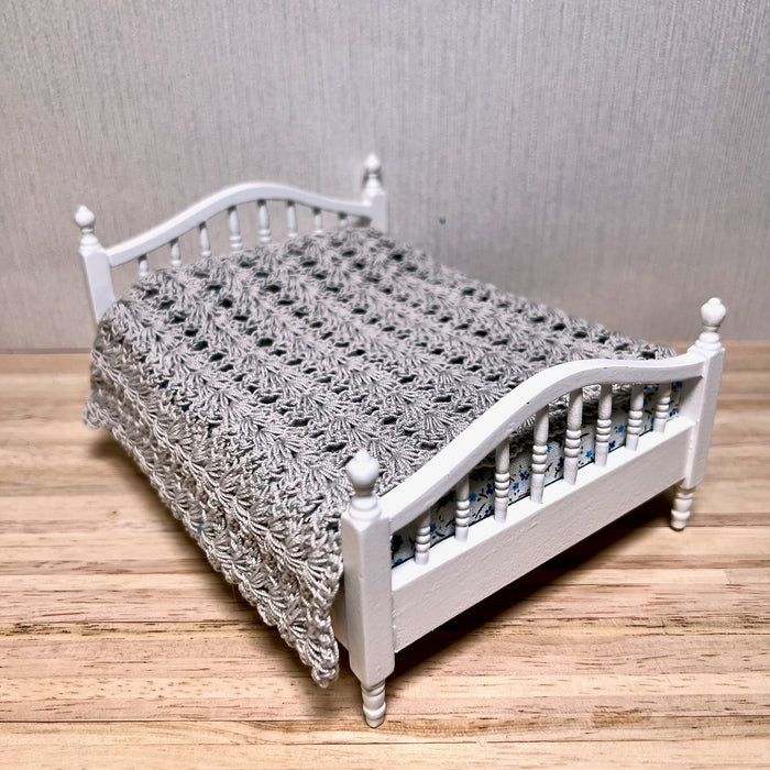 Harmaa parisängyn päiväpeitto.