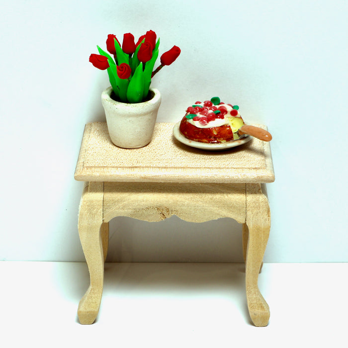 Miniatyyrikakku ja kukkia pikkupöydällä.