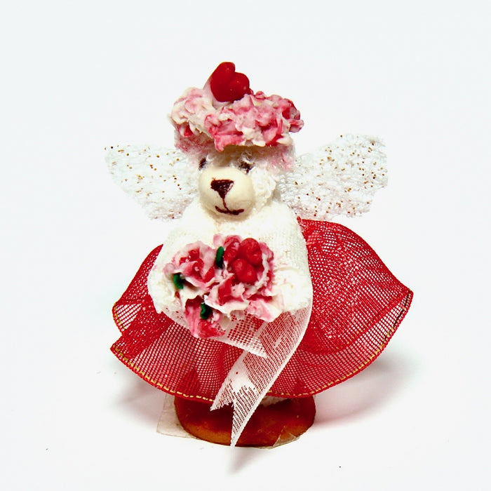 A teddy bear, a red dress and a wreath of flowers