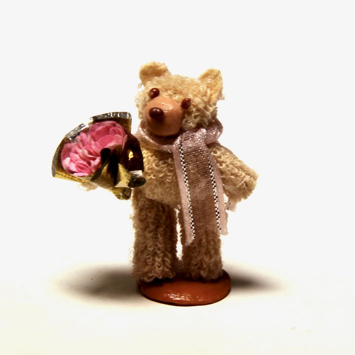 A light brown teddy bear with a bouquet of flowers